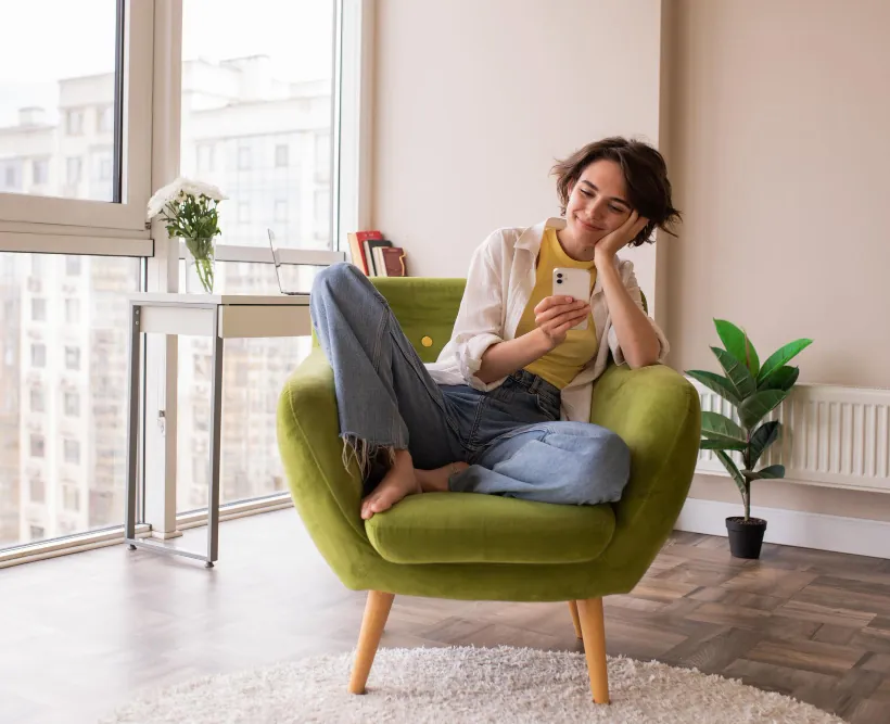 Locataire souriante installée dans un fauteuil de son appartement
